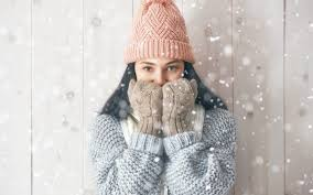 Woman applying face cream in winter, cozy setting